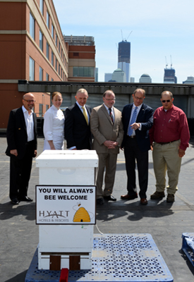 Photo of officials on the roof of the Hyatt Regency Jersey City with a new resident beehive.