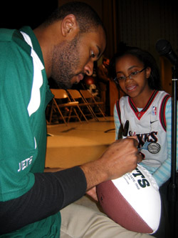 Photo of NY Jets Marques Murrell signing a football for a student