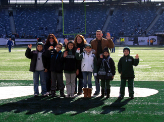 Photo of school representatives on the field at the Jets game.