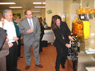 Photo of Rose Tricario demonstrating the orange juice machine at School 2