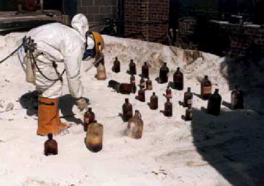 Photo 3 - Unknown chemicals being staged by a worker in Level B protective clothing for consolidation during the 1985 emergency clean up. 