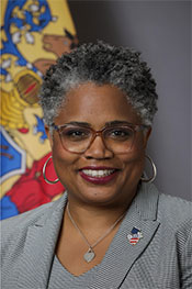 Headshot of Angelica Allen-McMillan, Ed.D. with the New Jersey state flag in the background