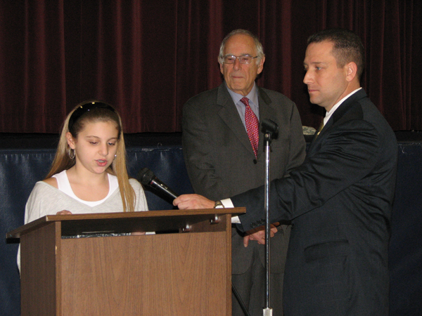 A Woodcliff Middle School 6th grade student reads her letter to soldiers while Principal Jack Leonard and State School Board Vice Chair Ilan Plawker look on.