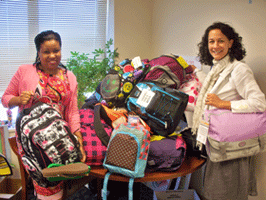 Commissioner Velez and Community Outreach Director Riva Thomas stand with piles of backpacks donated by DHS employees for the 2009 Back to School Backpack Drive.