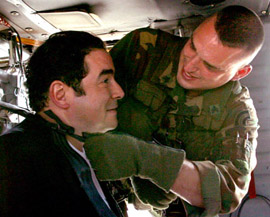 Blackhawk crewchief Sgt. Eric Chambers (right) straps in Emeril Lagasse
        (left) prior to taking off. Photo by Tech. Sgt. Mark Olsen, NJDMAVA/PAO.