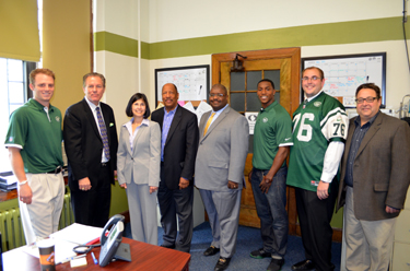 Photo of officials gathered with NY Jets players Greg McElroy and Julian Posey
