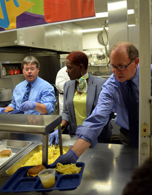 Photo of Jim Harmon, Cherrie Walker and Secretary Fisher serving lunch.