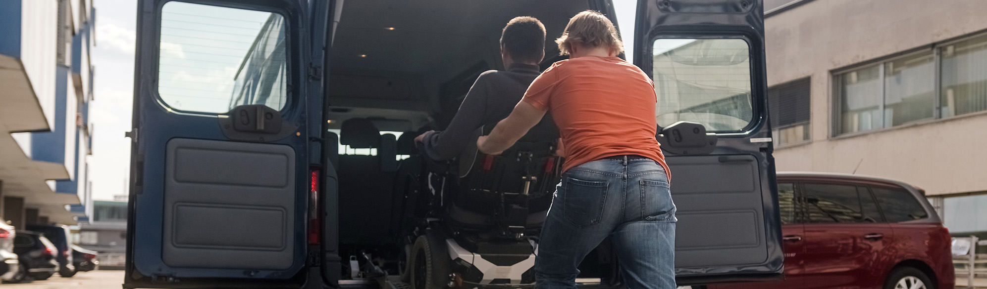 Person in a wheel chair being helped into transport
