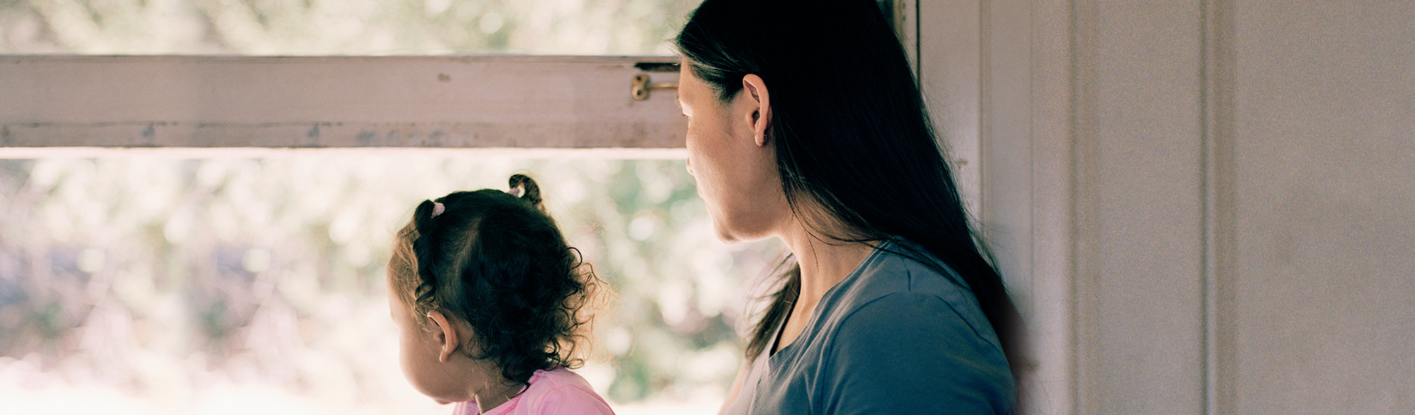 Mother holds child in lap and looks out window