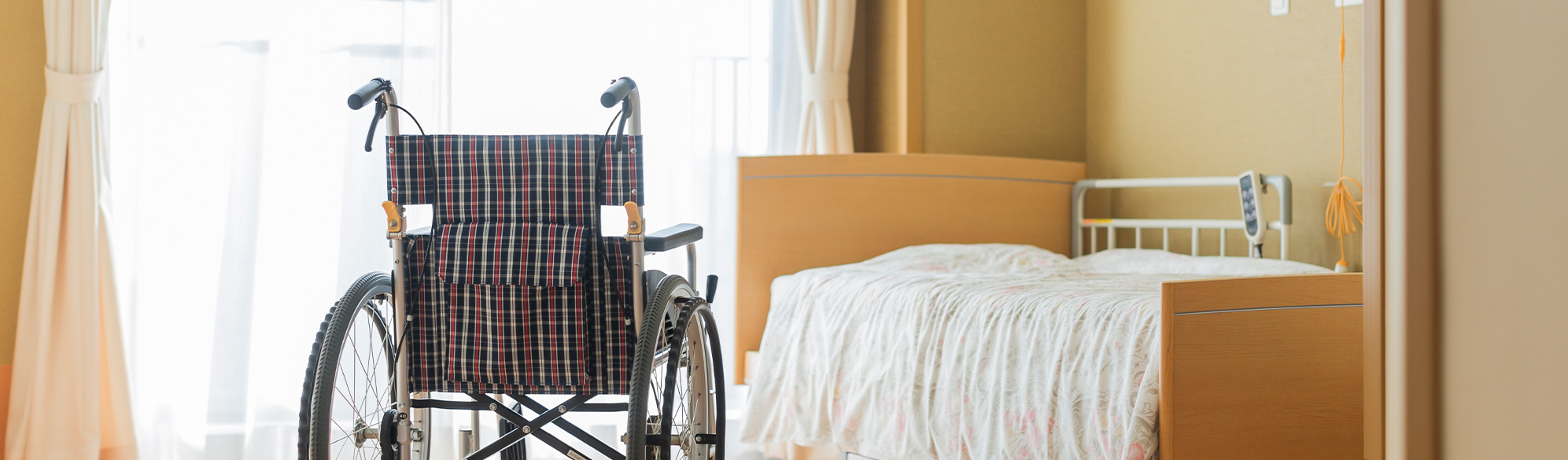 An empty bed and empty wheelchair in a nursing home