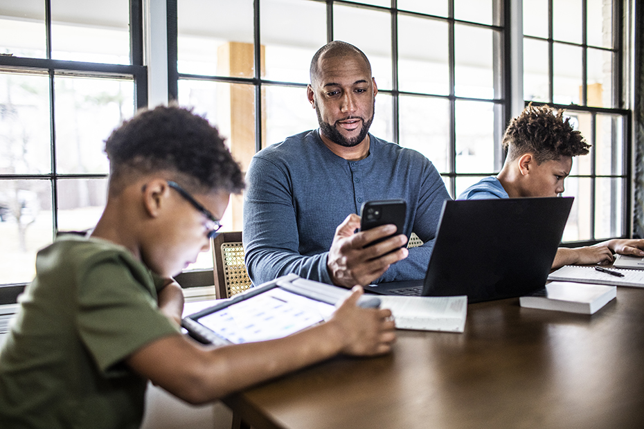 Kids and parent sitting at table with internet devices