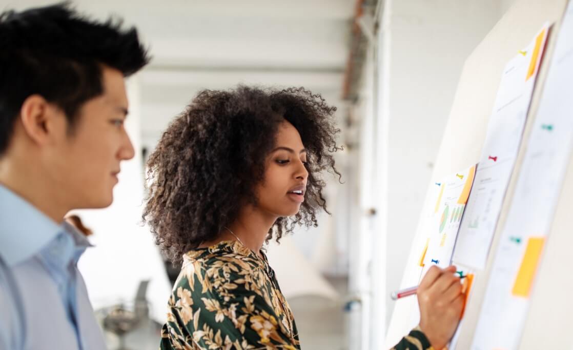 photo: a men and women by a board