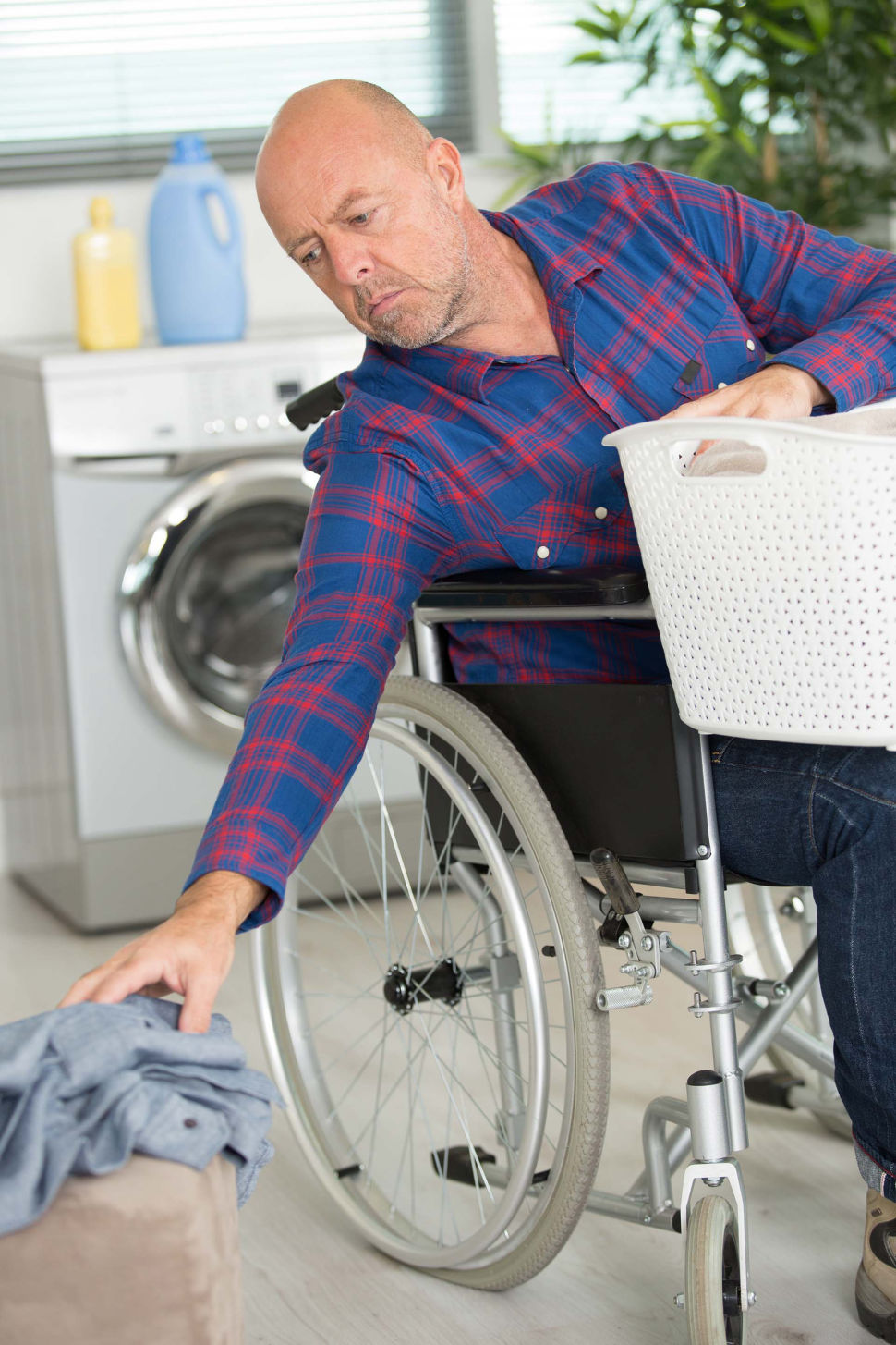 man in wheel chair picking up laundry