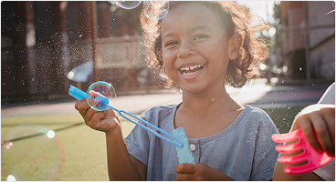 Photo of a child smiling and blowing bubbles