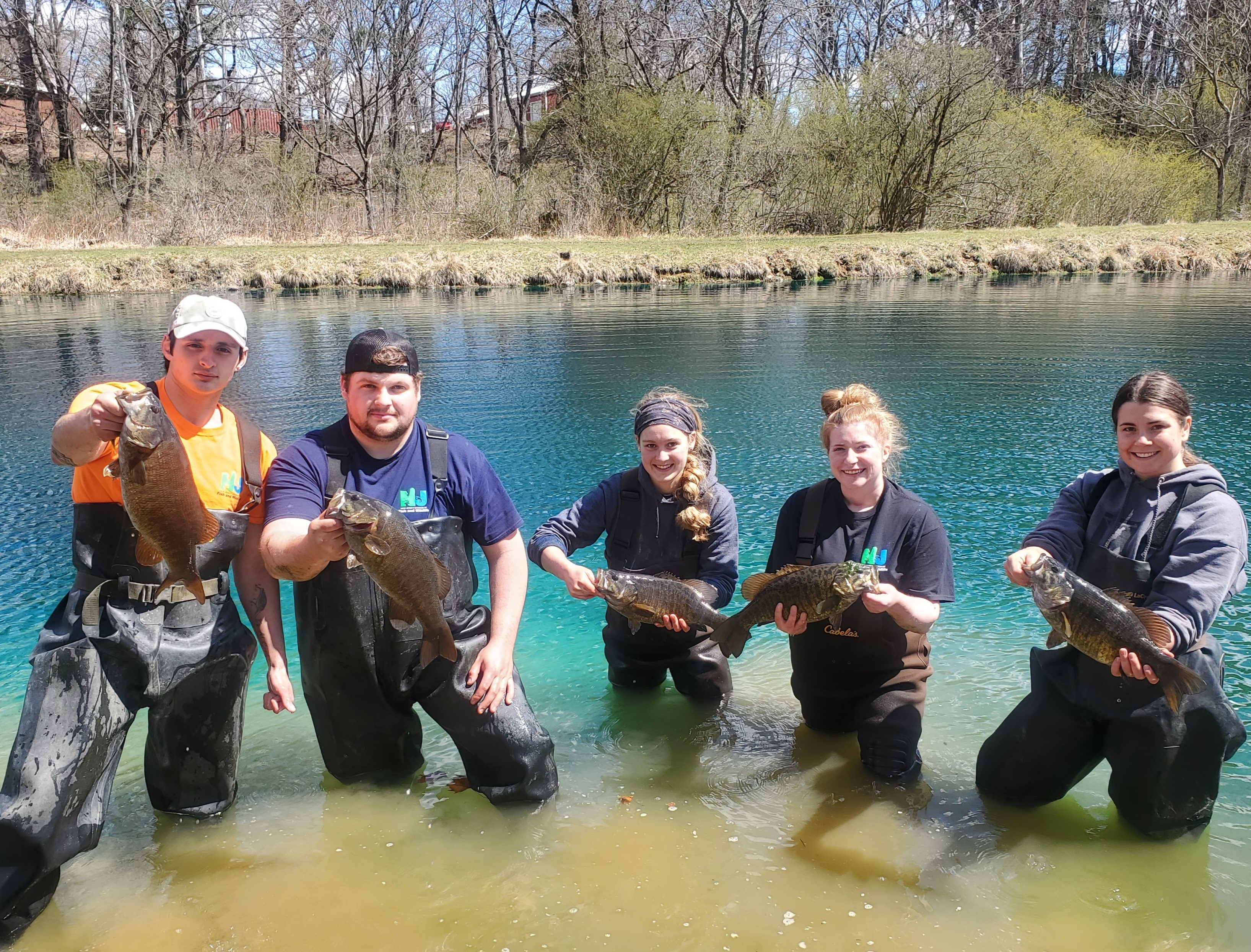 Photo of Young Adults in Water Holding Bass Photo of Young Adults in Water Holding Bass