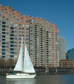 A white sailboat on the Hudson River with New York City's skyscrapers in the backdrop