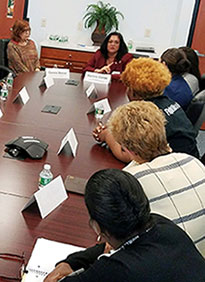 Department of Banking and Insurance Acting Commissioner Marlene Caride discusses the importance of health care with residents and clients at HomeFront Family Campus in Ewing. Left to Right: Connie Mercer, HomeFront Executive Director; Acting Commissioner Caride; Meghan Davey, Director of the Division of Medical Assistance and Health Services, Department of Human Services; and HomeFront clients and staff. 