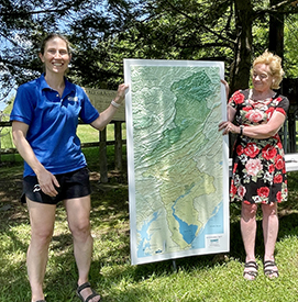 DRBC Director of External Affairs & Communications Elizabeth Brown poses with UDC Executive Director Laurie Ramie and a large 3D map of the DRB. These maps were produced as part of DRBC's Our Shared Waters program. Photo by the DRBC.