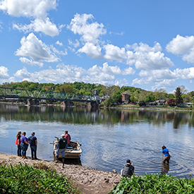 Macroinvertebrates are collected from the river. Staff (in waders) place the netdownstream and gently disturb the riverbottom upstream, collecting the bugs in the net. Photo by the DRBC.