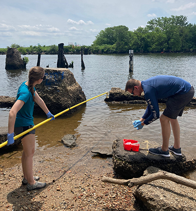 DRBC Water Quality Interns Kyle McAllister and Bailey Adams (L) collect a water sample to monitor bacteria levels. Photo by DRBC.