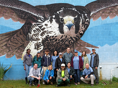 DRBC and N.J. District 7 legislative volunteers pose for a photo in front of Palmyra Cove's peregrine falcon mural after a successful cleanup. Photo by DRBC.