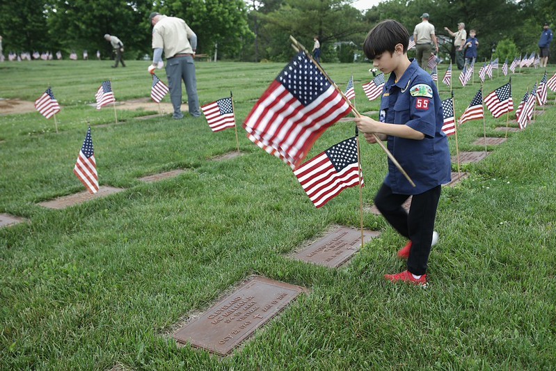 Boy scout placing a flag on a grave at Brigadier General William C. Doyle Veterans Memorial Cemetery 