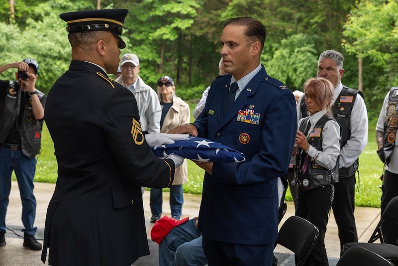 Air force Col. receiving folded flag from Army Staff Sergeant. 
