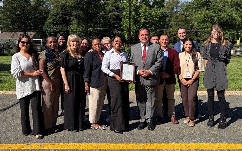 Commissioner Vincent Solomeno, Noelle Lee-Turner, and fellow DVA employees pose with letter from Governor Mikie Sherrill.