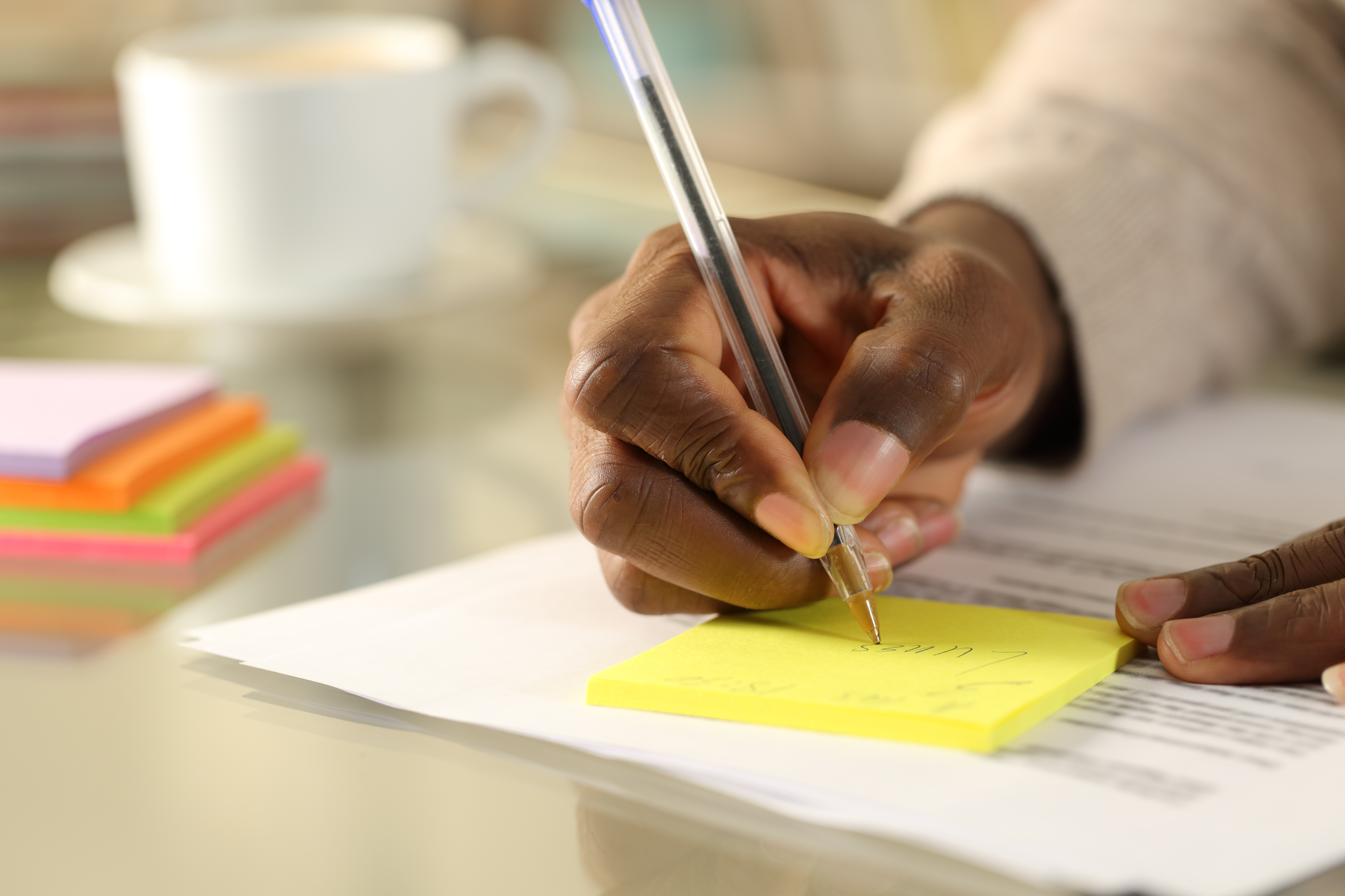 picture of an African American educator's hands taking notes on paper in a white shirt with the stamp reading 