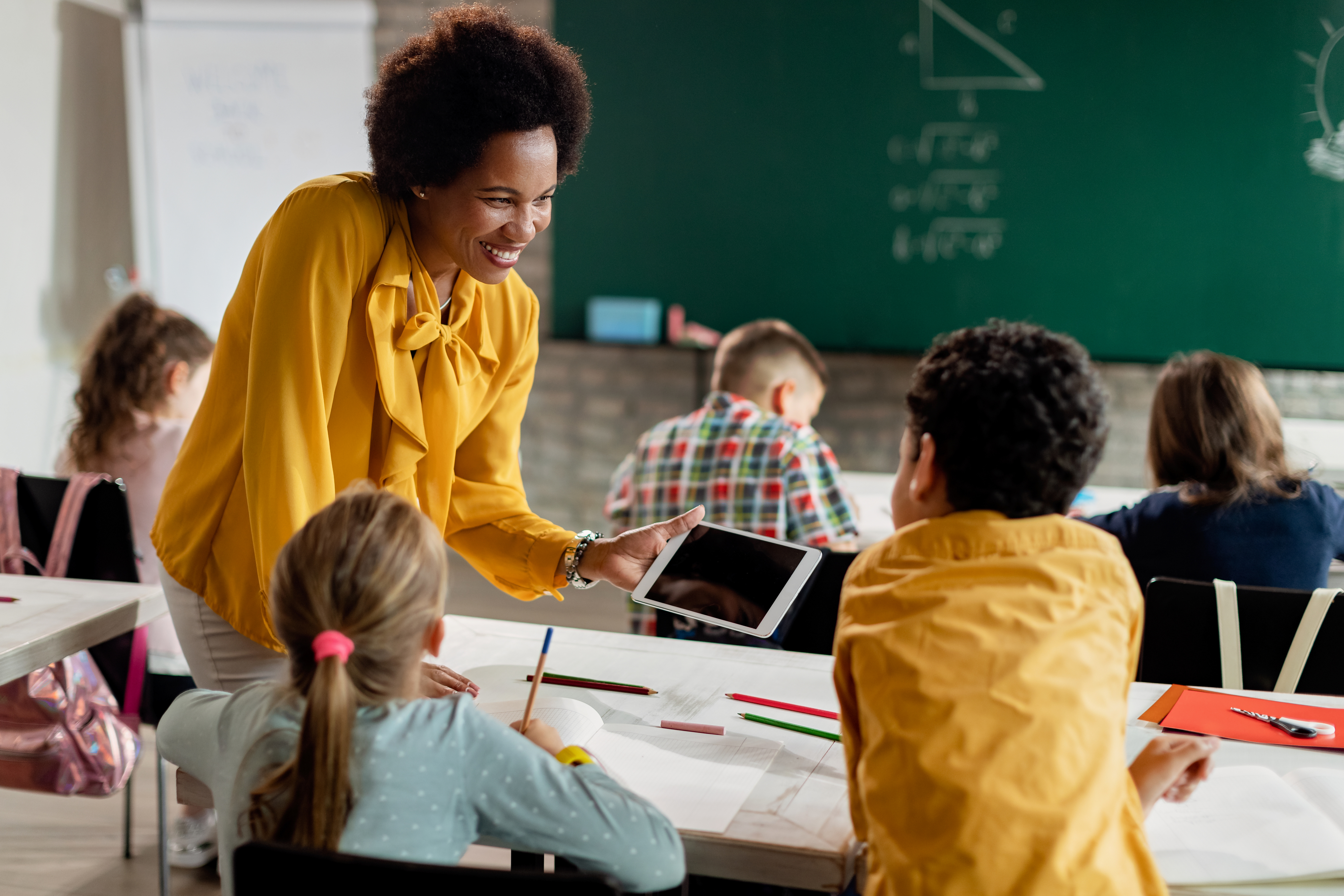 african american teacher assisting two students while holding an IEP