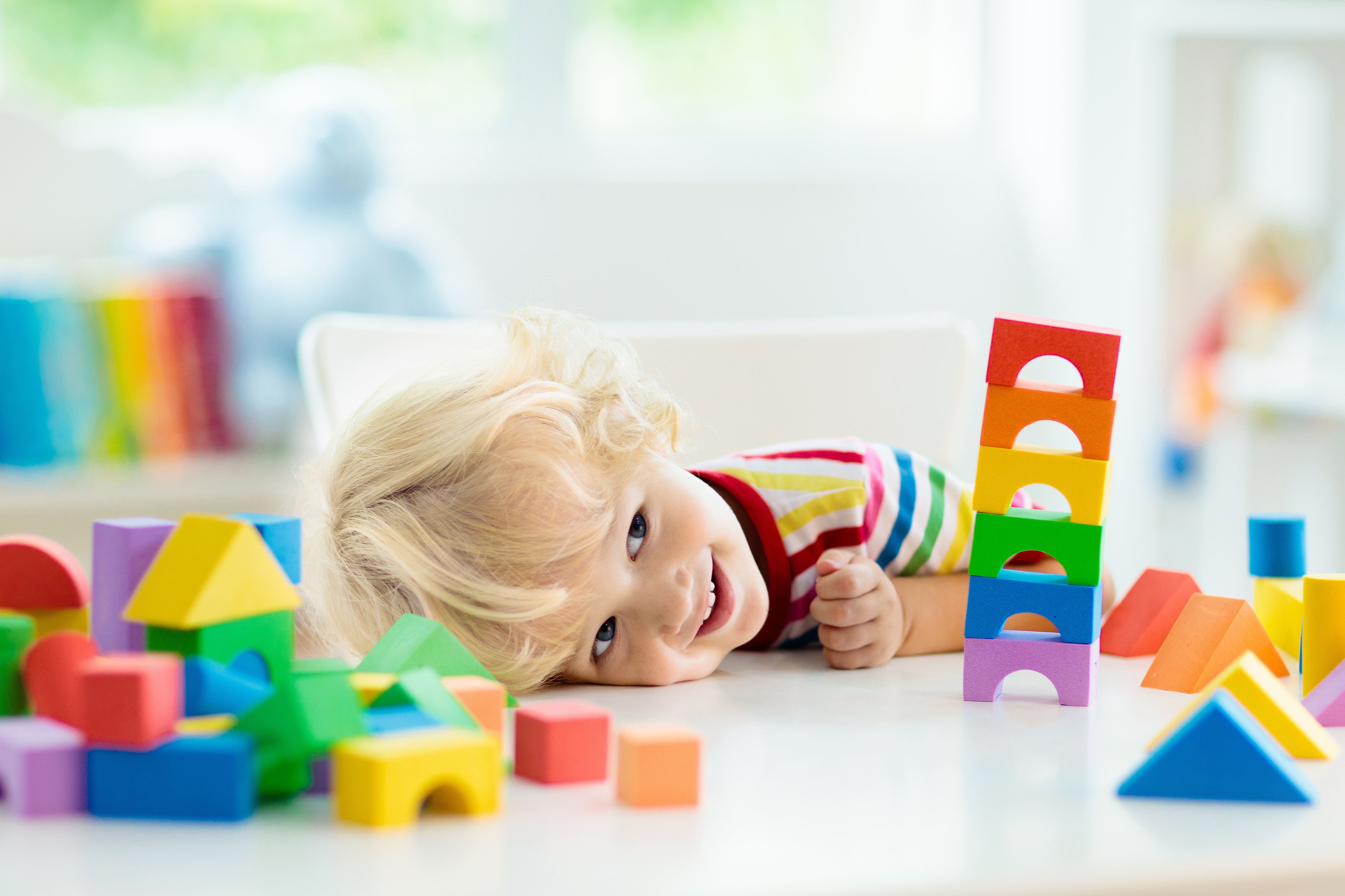 Student with blonde hair laying his head on the table looking at his stack of blocks