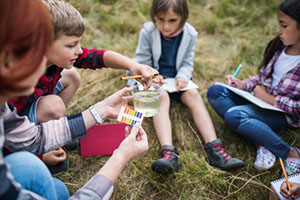 Elementary students sitting outside on the grass running an experiment