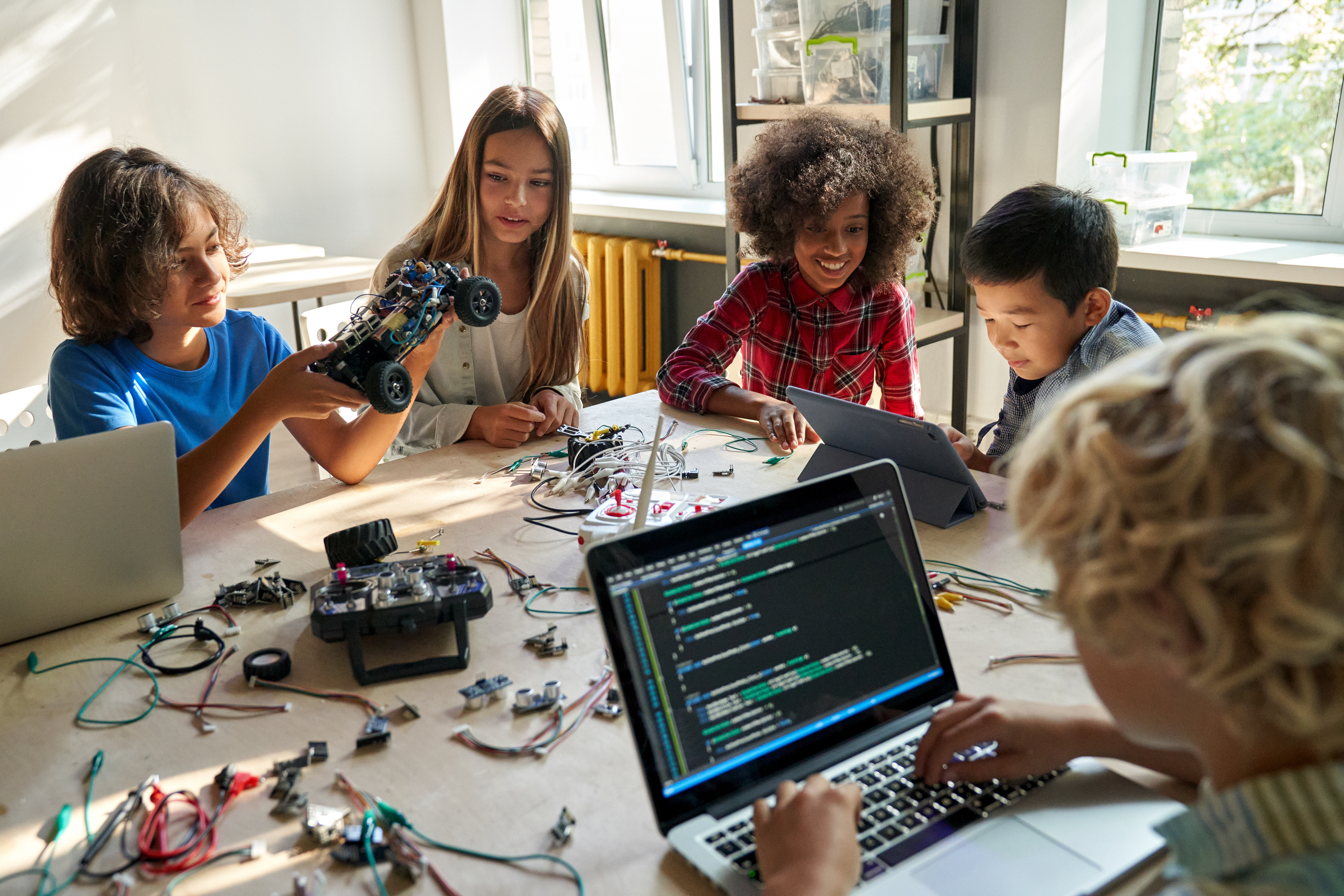 Middle school students working on computers and robotic equipment