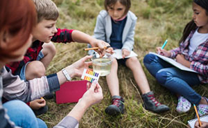 Elementary students sitting outside on the grass running an experiment