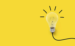 Yellow background with a light bulb that is lit