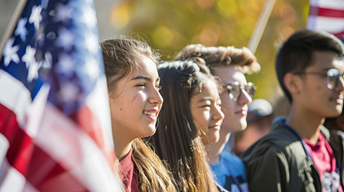 American flag in the forefront, high school students behind the flag