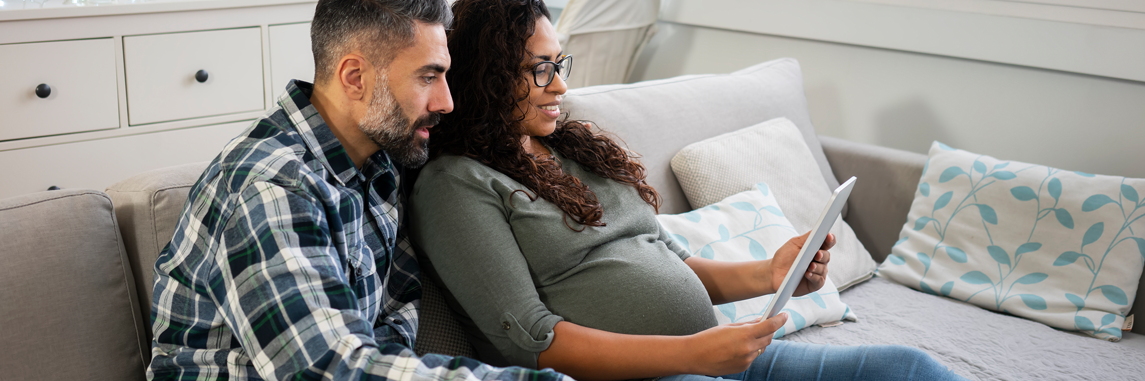 photo: couple holding tablet; woman is pregnant