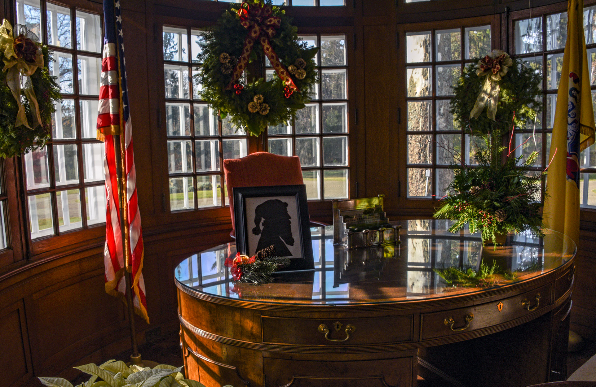 Bow windows in the Governors Study, decorated with festive wreaths and framed Santa profile on the desk.