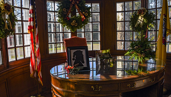 photo - Bow windows in the Governors Study, decorated with festive wreaths and framed Santa profile on the desk.