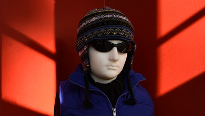 photo - Just outside the Governors Study, a bust of a young man is whimsically dressed in ski gear and sunglasses. Geometric patches of sunlight on crimson walls frames the figure.
