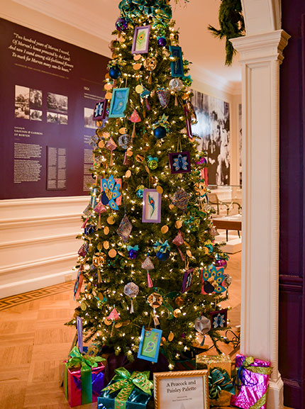 photo - A “Peacocks and Paisley Palette Christmas” tree by West Trenton Garden Club is seen in the Foyer with many vibrant colors. On the walls across and behind are historical displays.