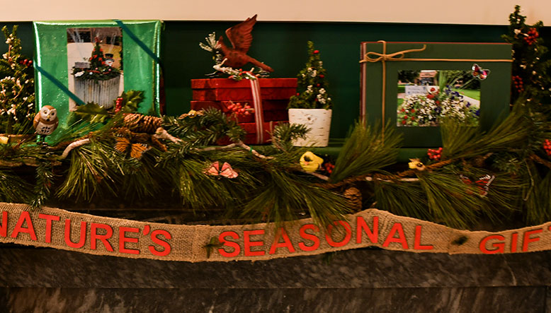 photo - A close photo of a decorated mantelpiece entitled “Natures Seasonal Gifts” by Nottingham Garden Club of Hamilton Township. Realistic bird figures and brightly colored packages with evergreens and berries are creatively displayed.