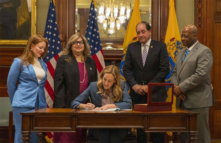 Governor Mikie Sherrill today signing legislation , sitting behind a desk