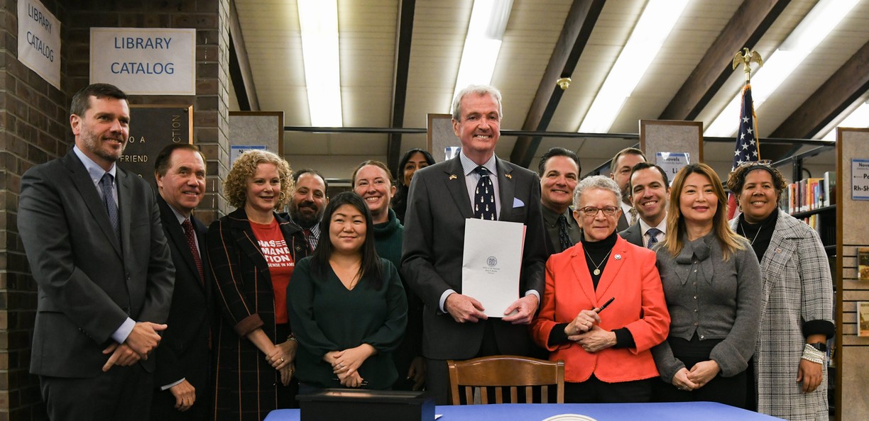 photo: Governor Phil Murphy holding a signed bill with people