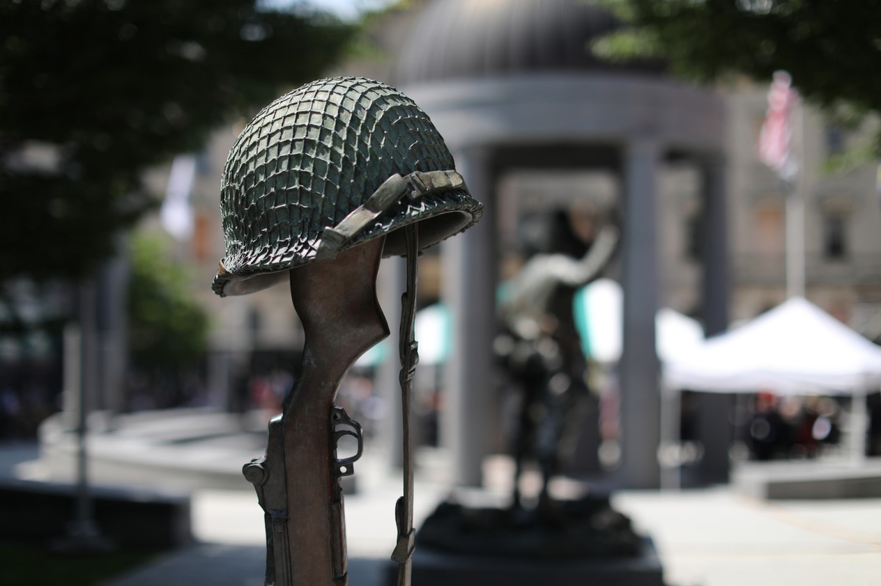 Image: Military helmet is hanging on the rifle with monument on the background