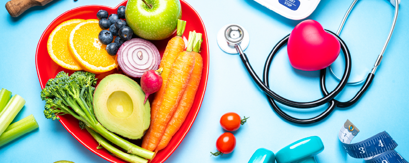 bowl of fruit and veggies, stethoscope, hand weights, tape measure, heart shape, and blood pressure monitor