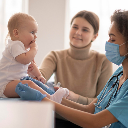 A baby getting a checkup while mom watches.