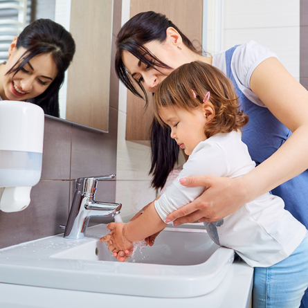 A parent helping their child wash their hands.