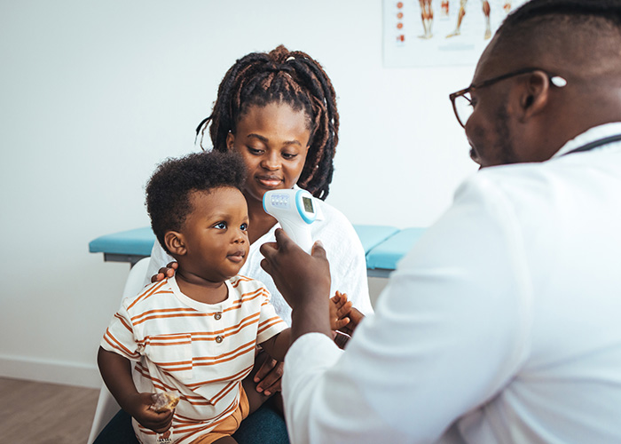 M&eacute;dico revisando si el ni&ntilde;o tiene fiebre.