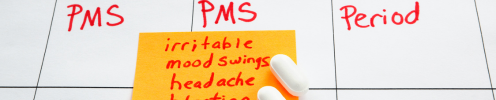 Calendar with a sticky note that described a few symptoms of PMS including: irritable, mood swings, and headache.